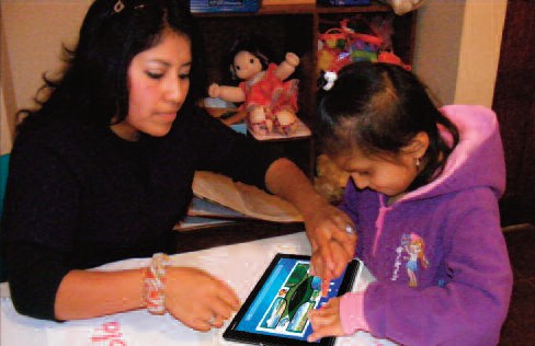 Maestra instruyendo a una niña en el uso del juego interactivo en una tablet