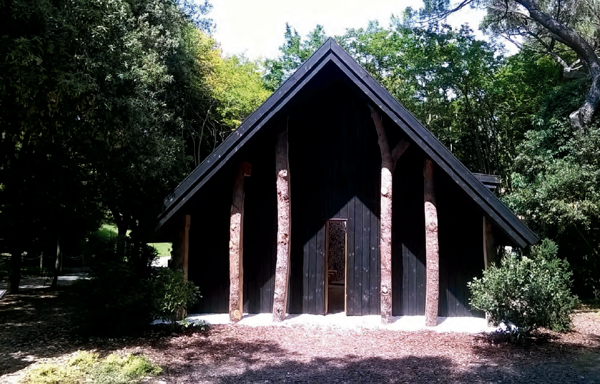 La capilla de Terunobu Fujimori es una cabaña con un porchedelimitado por troncos de árboles y una estrecha puerta de entrada