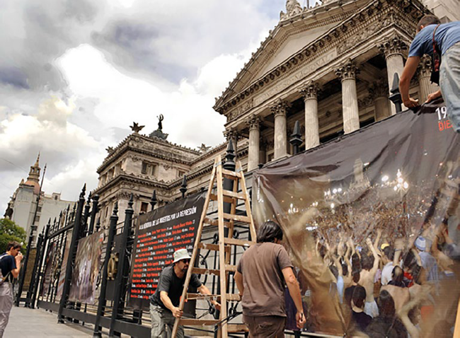 Fotografía en la instancia de colgar las gigantografías en la reja del Palacio del Congreso