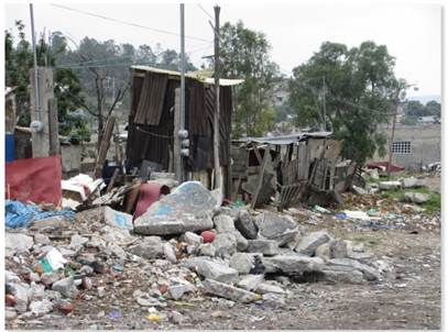 Avenida Ecología con el Parque Estatal de fondo. Se observan las viviendas precarias y escombros de basura