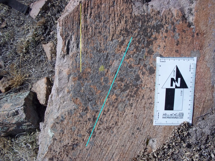 Fotografía apuntando al norte de un plano de falla de la Estación 3 En la estructura concurren dos conjuntos de estrías el más antiguo define líneas verticales parcialmente obliteradas mientras que el más reciente define líneas oblicuas