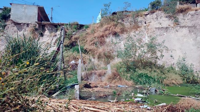 Colapso de infraestructura y calle por deslizamiento de ladera, con laguna formada por acumulaci&oacute;n de agua