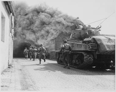Soldiers of the 55th Armored Infantry Battalion and tank of the 22nd Tank Battalion move through smoke filled street (1945)